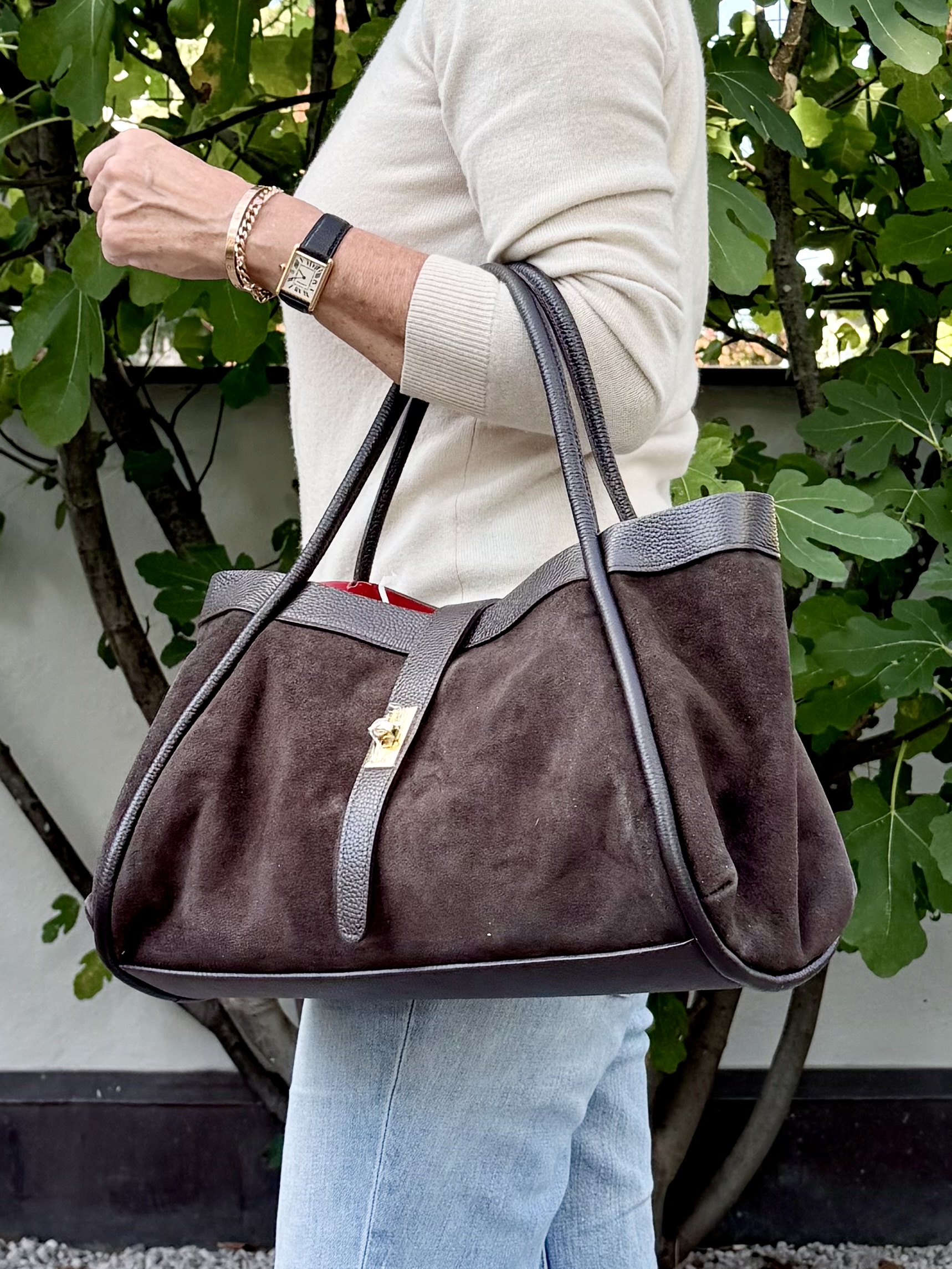 Wildleder Handtasche in Dunkelbraun mit rotem Innenfutter, am Unterarm getragen