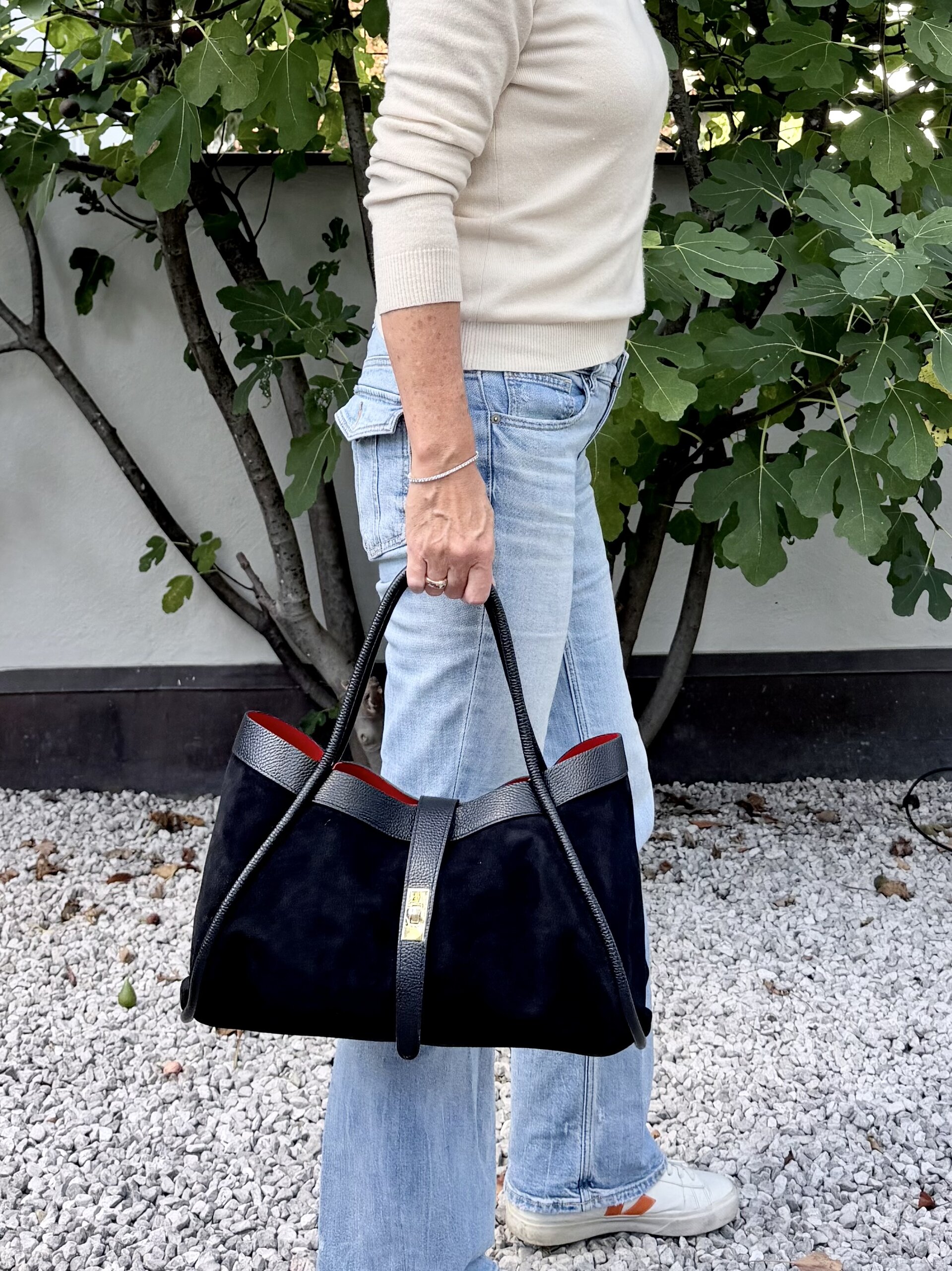 Wildleder Handtasche in Schwarz mit rotem Innenfutter, an den Henkeln getragen zu Jeans