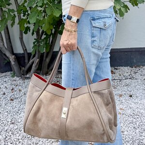 Wildleder Handtasche in Taupe mit rotem Innenfutter, in der Hand getragen zu Jeans